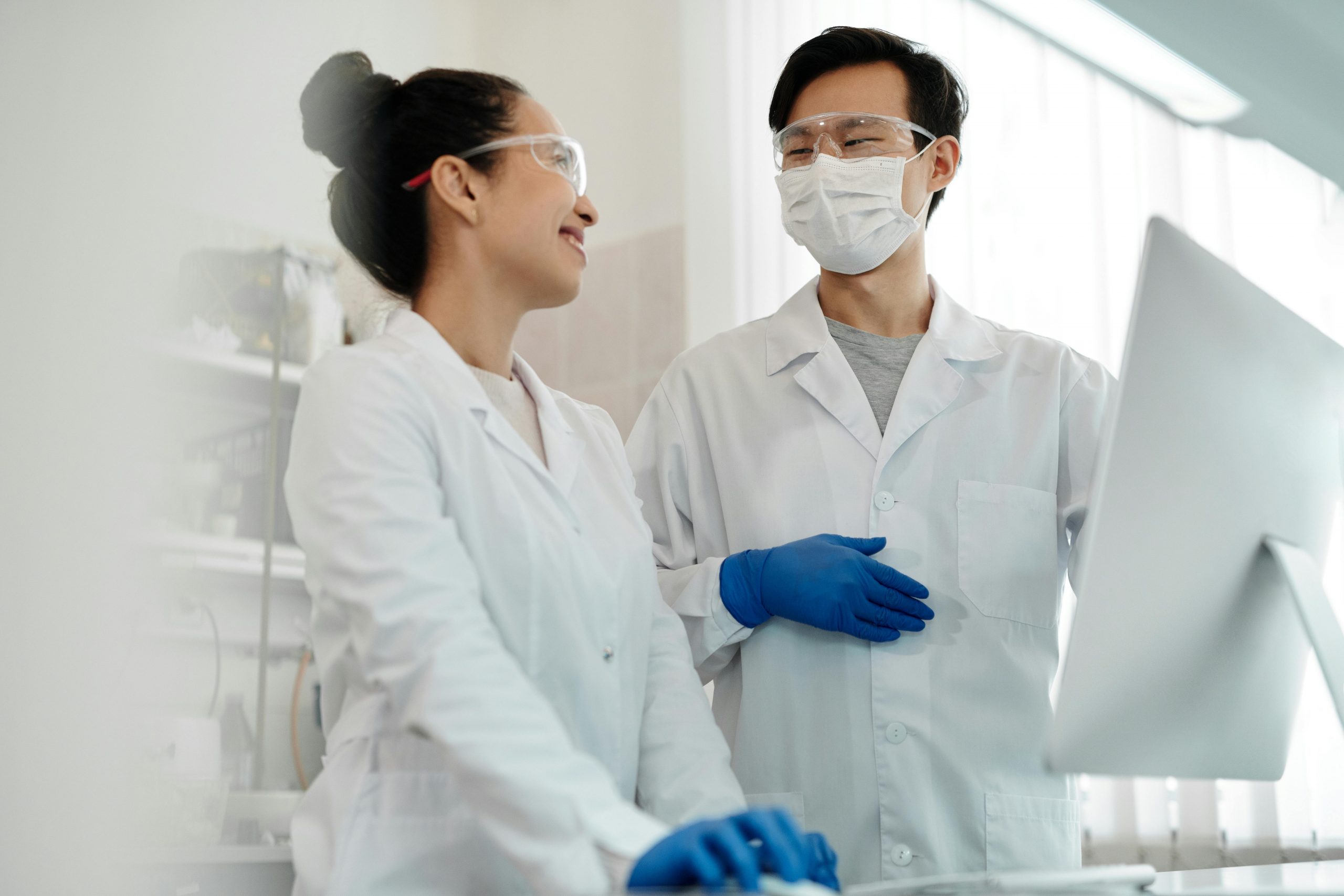 Two scientists wearing safety gear collaborate on a research project in a laboratory setting.